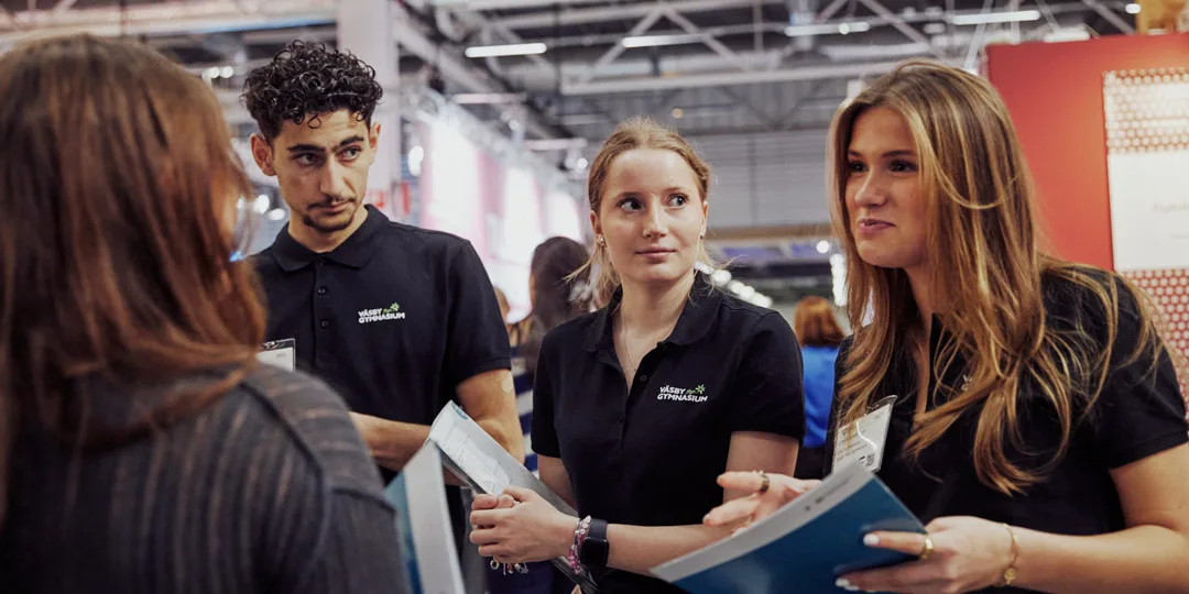 hallkarta-2024-1080x540 Tre utställare som pratar med en besökare