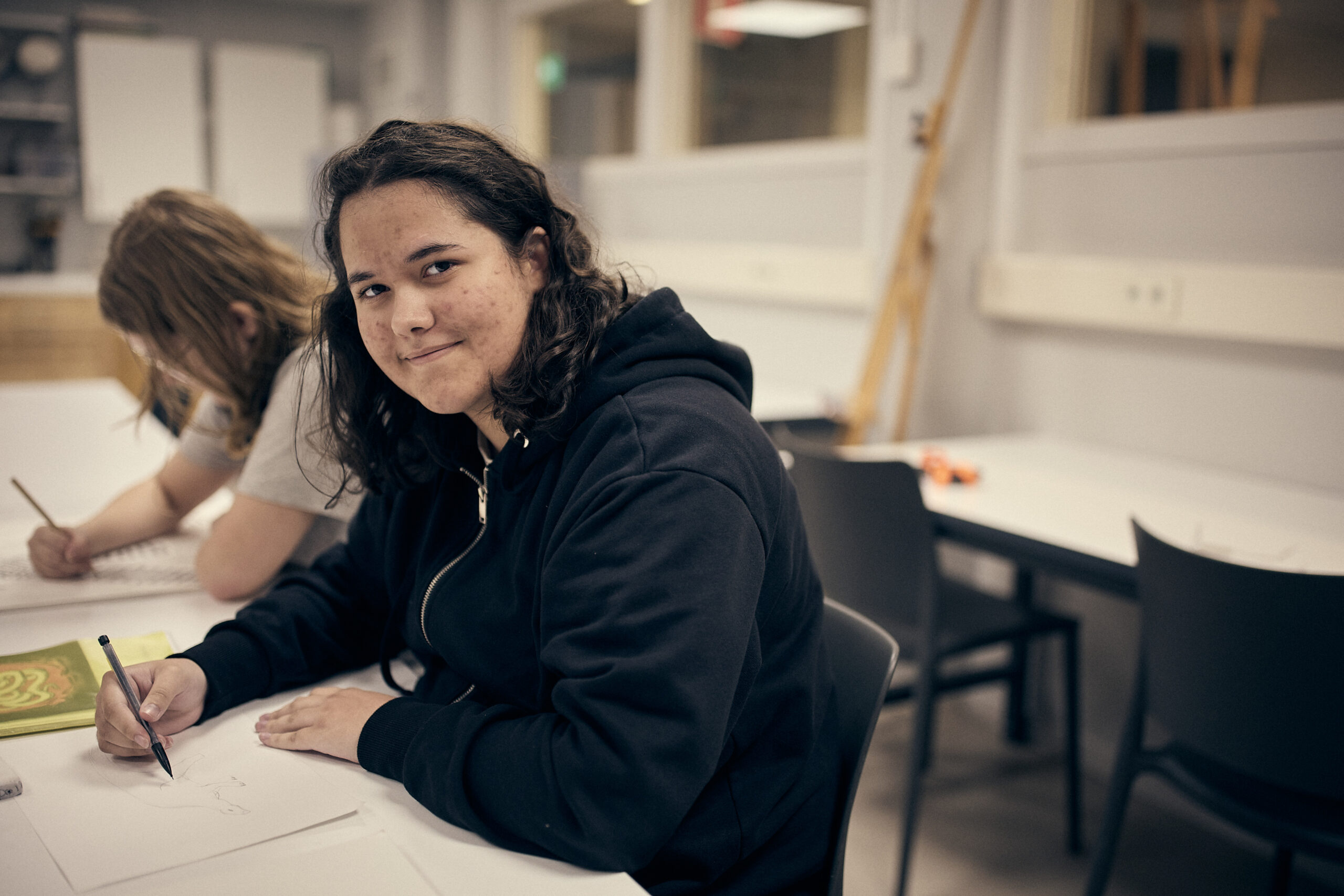 tjej vid skolbänk som tittar in i kameran